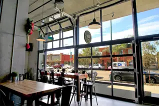 View through an open glass door inside a brewery taproom